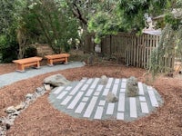 a garden with benches and stones in the middle