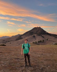 a man standing in a field at sunset